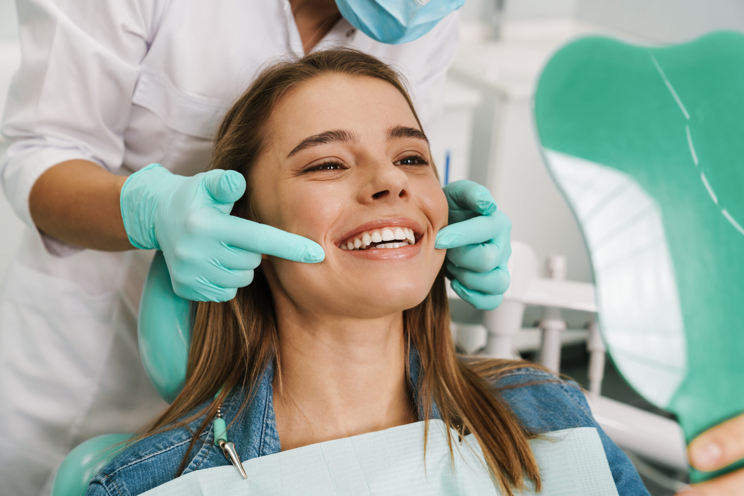 European young woman smiling while looking at mirror in dental c